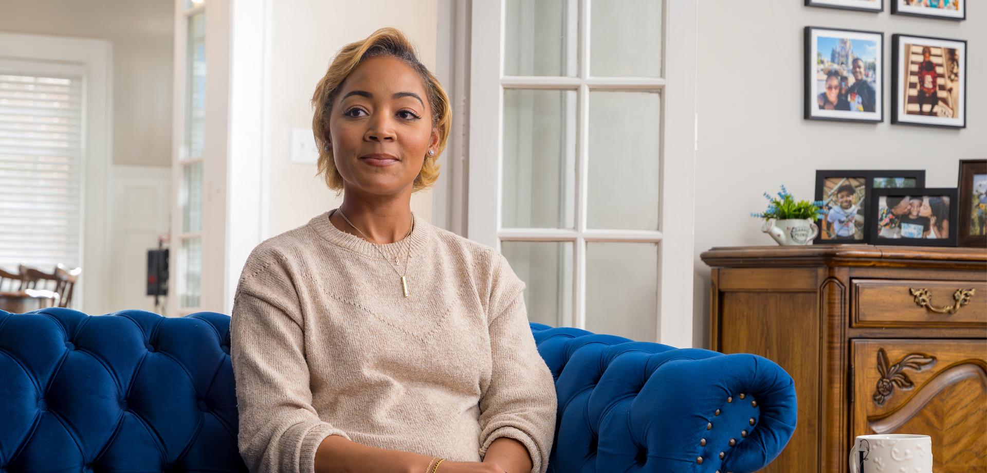 Woman sitting on a blue couch, looking ahead with a slight smile.