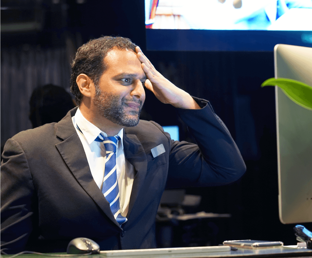 A man in a suit and tie intently gazes at a computer screen, focused on his work.