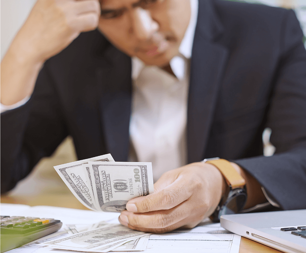 A man in a suit confidently holds a large stack of cash, showcasing financial success and professionalism