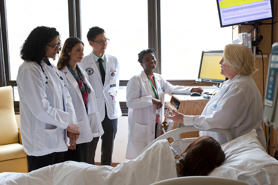 Image of Doctor talking to a room of medical students while a patient lays down near by