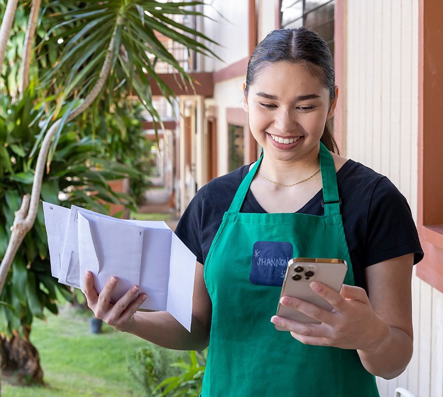 Female looking at mobile device with ASB personal debit card