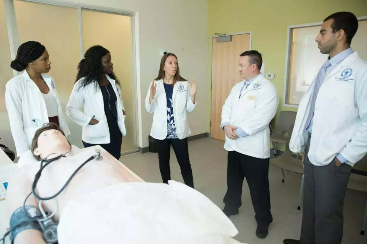 Multiple students listening to teacher in white coat