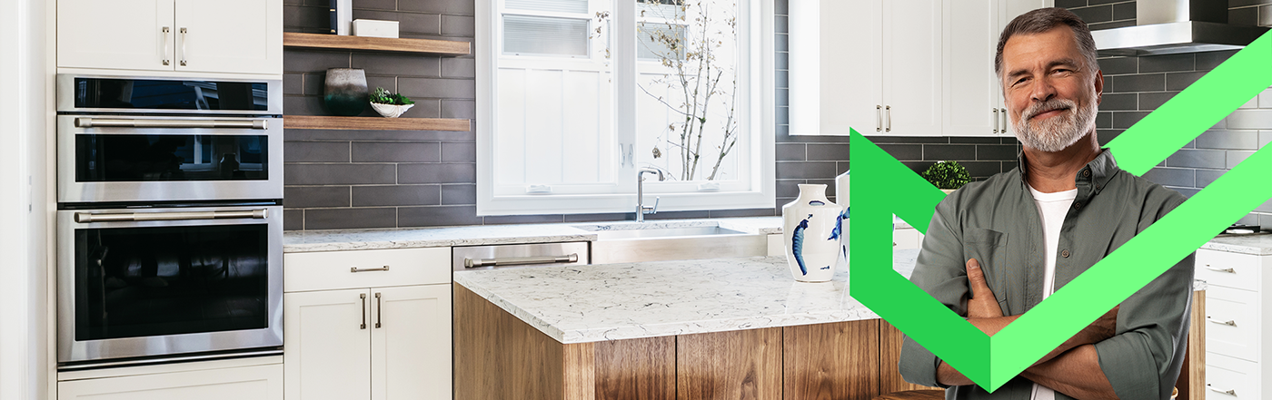 Older man standing in kitchen with arms folded and a Cinch checkmark wrapping his upper body