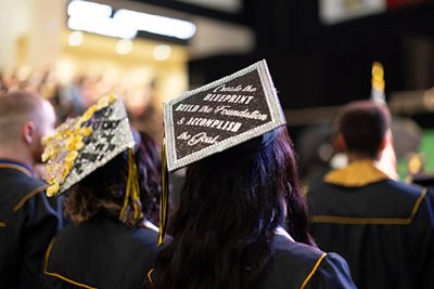 girl sitting at graduation with graduation cap and robe