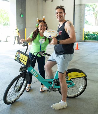 ASB teammate on a bike picking up pie from pie drive